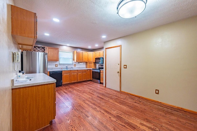 5102 Avalon Ave, Columbus, OH 43229 - kitchen featuring black appliances, wood finished floors, light countertops, recessed lighting, and a textured ceiling