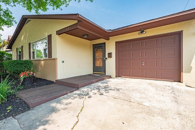 5102 Avalon Ave, Columbus, OH 43229 - view of front facade with stucco siding, driveway, and an attached garage