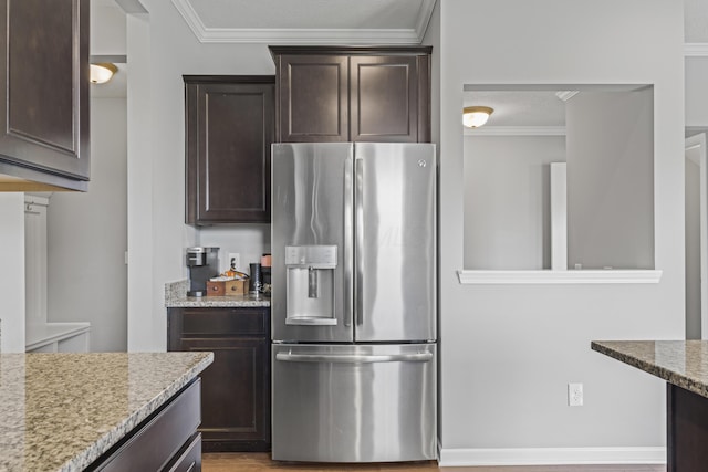 185 Saffron Dr, Sunbury, OH 43074 - kitchen with stainless steel fridge, dark brown cabinets, crown molding, light stone counters, and light wood finished floors