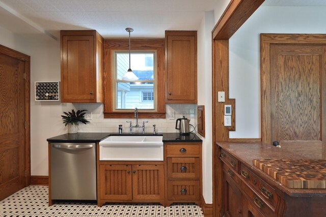 203 Winthrop Rd, Columbus, OH 43214 - kitchen with stainless steel dishwasher, a sink, dark countertops, brown cabinets, and decorative light fixtures
