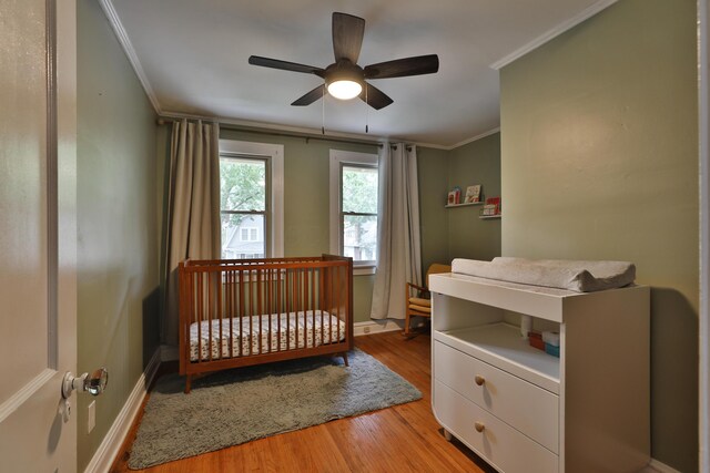 203 Winthrop Rd, Columbus, OH 43214 - bedroom featuring crown molding, light wood finished floors, a nursery area, a ceiling fan, and baseboards