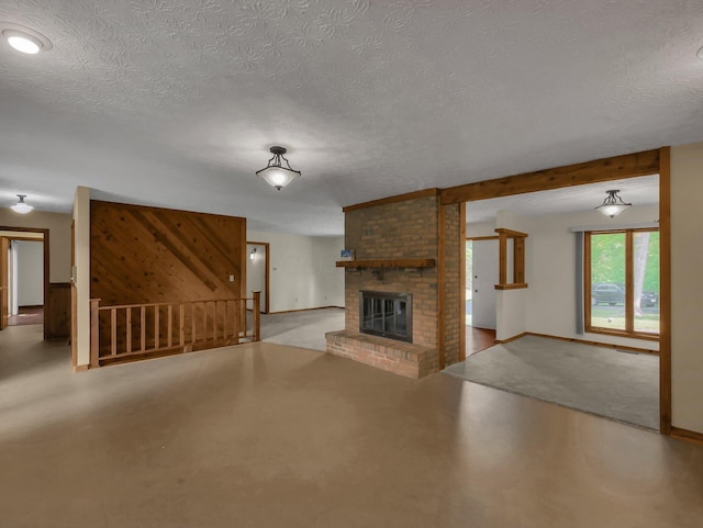8587 Blacks Rd, Pataskala, OH 43062 - unfurnished living room with a textured ceiling, finished concrete flooring, a brick fireplace, baseboards, and stairs