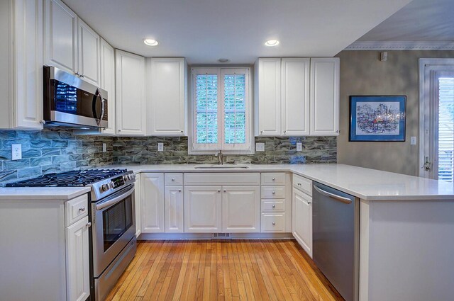 651 S 6th St, Columbus, OH 43206 - kitchen featuring stainless steel appliances, a peninsula, a sink, light wood-type flooring, and backsplash