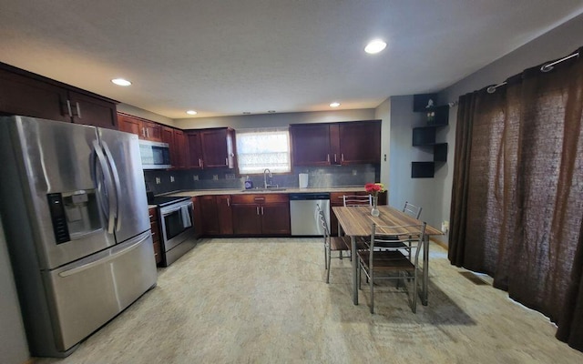 3230 Saint Bernard Cir, Columbus, OH 43232 - kitchen featuring appliances with stainless steel finishes, a sink, reddish brown cabinets, decorative backsplash, and light countertops