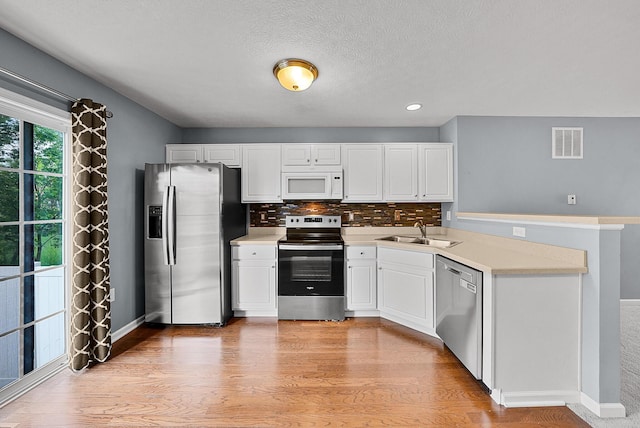 5801 Bridgehampton Dr, New Albany, OH 43054 - kitchen with appliances with stainless steel finishes, a peninsula, white cabinetry, light countertops, and a textured ceiling