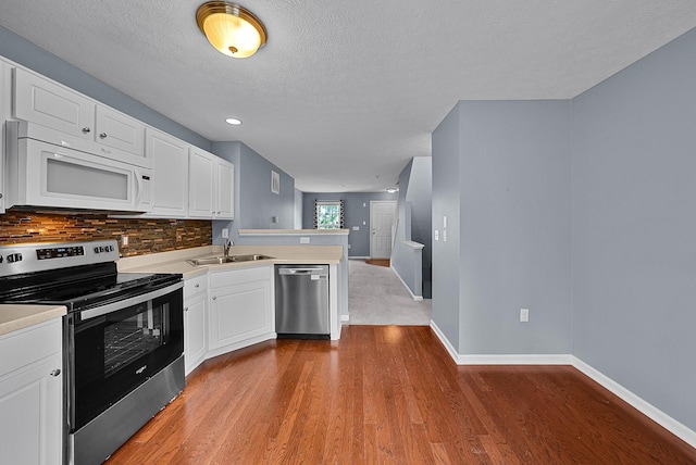 5801 Bridgehampton Dr, New Albany, OH 43054 - kitchen with stainless steel appliances, a peninsula, wood finished floors, tasteful backsplash, and white cabinets