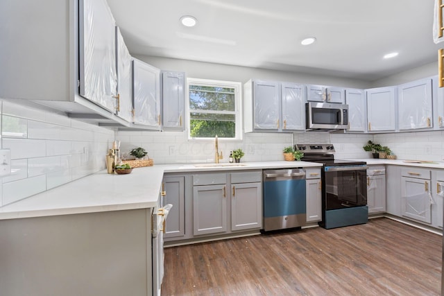 1271 Moundview Ave, Columbus, OH 43207 - kitchen with stainless steel appliances, a sink, dark wood-type flooring, decorative backsplash, and light countertops