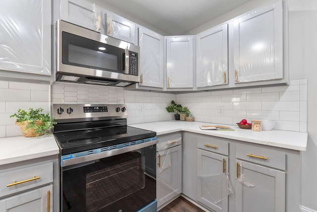 1271 Moundview Ave, Columbus, OH 43207 - kitchen with stainless steel appliances, light countertops, backsplash, and dark wood-style flooring