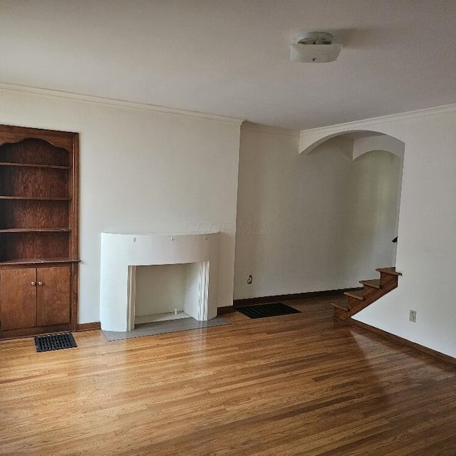 2325 E Livingston Ave, Columbus, OH 43209 - unfurnished living room with wood finished floors, ornamental molding, arched walkways, stairs, and baseboards