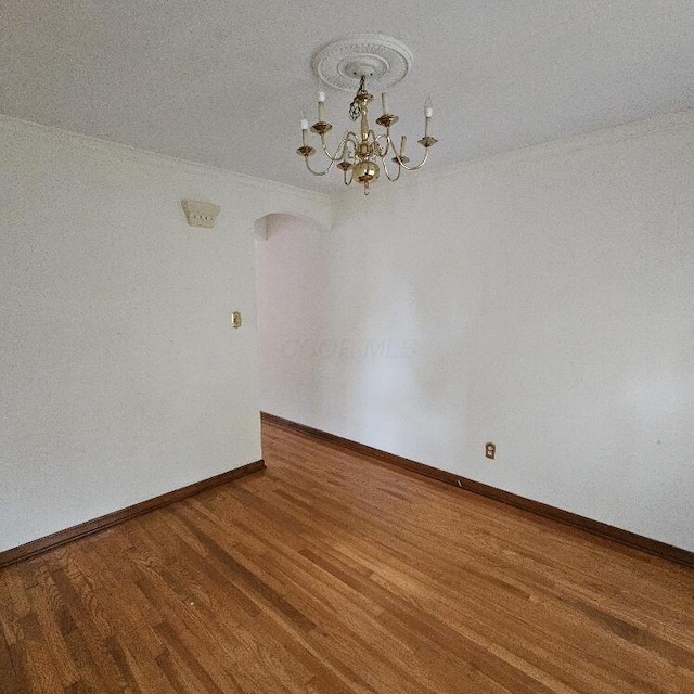 2325 E Livingston Ave, Columbus, OH 43209 - empty room featuring arched walkways, wood finished floors, a chandelier, and baseboards