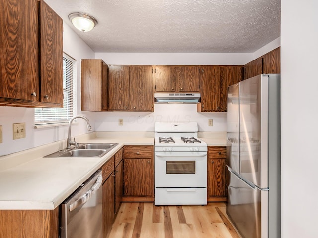 873 Soramill Ln Unit 4B, Columbus, OH 43085 - kitchen featuring stainless steel appliances, under cabinet range hood, a sink, light wood finished floors, and brown cabinets