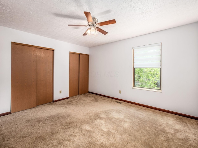 873 Soramill Ln Unit 4B, Columbus, OH 43085 - unfurnished bedroom with two closets, carpet, baseboards, a ceiling fan, and a textured ceiling