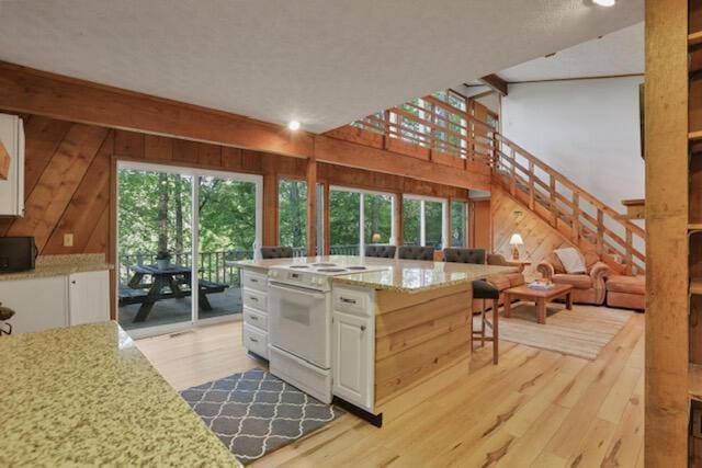 1275 Taos Ln, Sugar Grove, OH 43155 - kitchen featuring white range with electric stovetop, white cabinetry, light wood-style flooring, wood walls, and light stone countertops