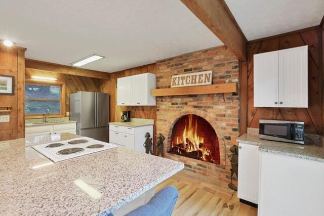 1275 Taos Ln, Sugar Grove, OH 43155 - kitchen featuring stainless steel appliances, wood walls, light wood-style flooring, white cabinets, and a sink