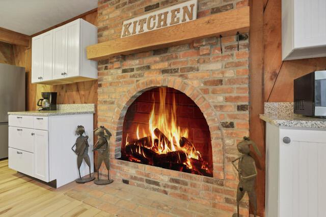1275 Taos Ln, Sugar Grove, OH 43155 - detailed view of freestanding refrigerator, a brick fireplace, and wood finished floors