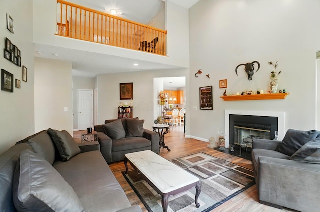 583 Marhurst Ct, Galloway, OH 43119 - living room featuring wood finished floors, a high ceiling, a fireplace with flush hearth, baseboards, and recessed lighting