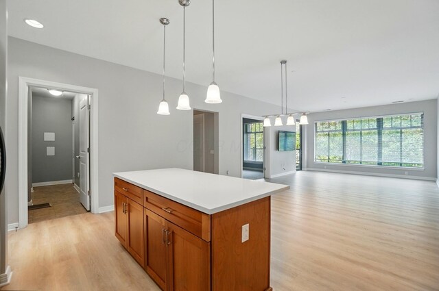250 Daniel Burnham Sq Unit 304, Columbus, OH 43215 - kitchen with light wood-style floors, a kitchen island, light countertops, open floor plan, and pendant lighting