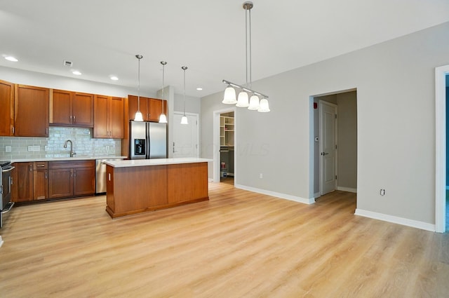 250 Daniel Burnham Sq Unit 304, Columbus, OH 43215 - kitchen featuring appliances with stainless steel finishes, a kitchen island, light countertops, light wood-style floors, and tasteful backsplash
