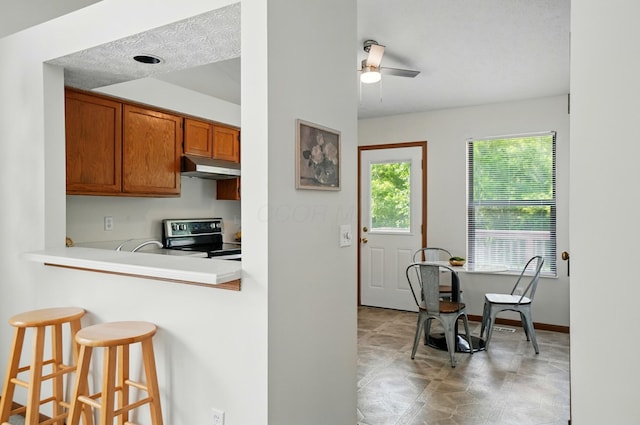 4557 Hidden Ridge Ct, Columbus, OH 43230 - kitchen featuring electric stove, under cabinet range hood, a breakfast bar area, brown cabinets, and ceiling fan
