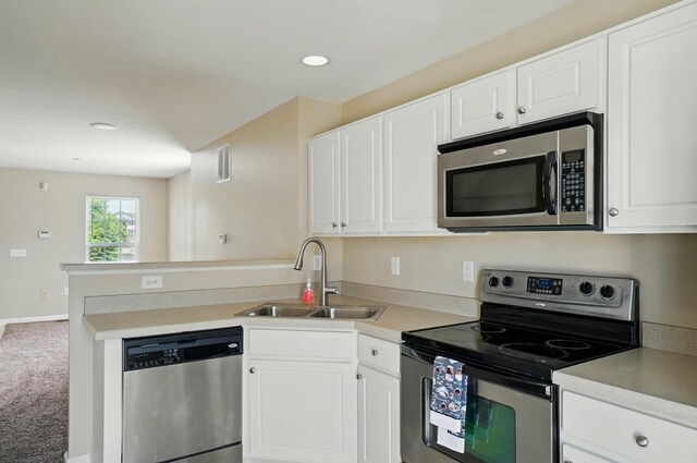 5629 Middle Falls St, Dublin, OH 43016 - kitchen with appliances with stainless steel finishes, a peninsula, carpet flooring, white cabinetry, and recessed lighting