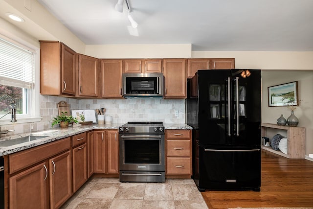 677 E Weisheimer Rd, Columbus, OH 43214 - kitchen with appliances with stainless steel finishes, a sink, light stone counters, and brown cabinetry