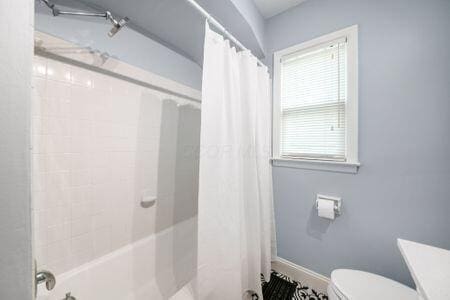 677 E Weisheimer Rd, Columbus, OH 43214 - bathroom featuring shower / bathtub combination with curtain, toilet, and baseboards
