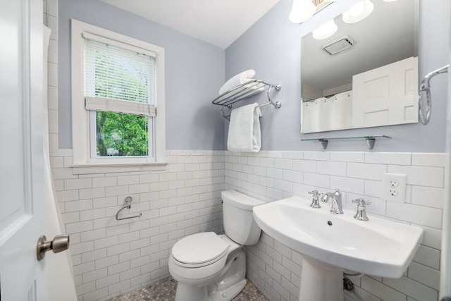677 E Weisheimer Rd, Columbus, OH 43214 - bathroom with tile walls, toilet, a wainscoted wall, and a sink