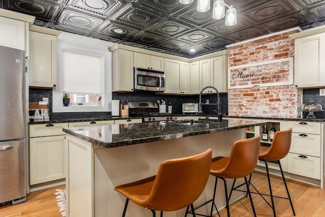 369 E Main St, Circleville, OH 43113 - kitchen with appliances with stainless steel finishes, an ornate ceiling, backsplash, light wood finished floors, and a kitchen island