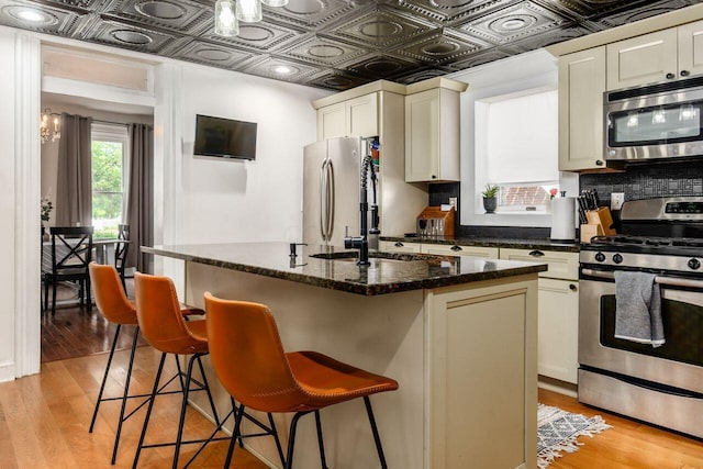 369 E Main St, Circleville, OH 43113 - kitchen featuring stainless steel appliances, an ornate ceiling, light wood-style floors, decorative backsplash, and a breakfast bar area