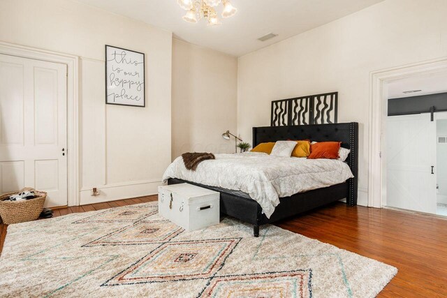 369 E Main St, Circleville, OH 43113 - bedroom with a barn door, wood finished floors, a chandelier, and baseboards