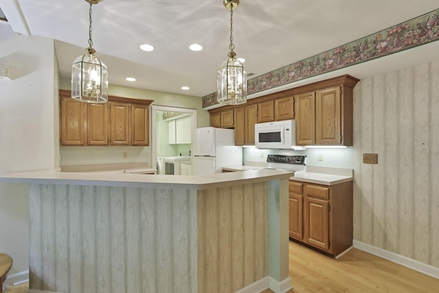 53 Stone House Ct, Newark, OH 43055 - kitchen featuring white appliances, independent washer and dryer, light wood-type flooring, a peninsula, and hanging light fixtures