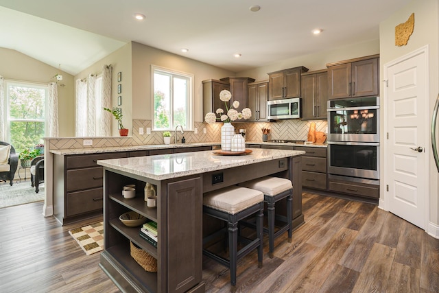 829 Pathlow Dr, Pickerington, OH 43147 - kitchen with stainless steel appliances, a kitchen island, dark brown cabinets, decorative backsplash, and lofted ceiling