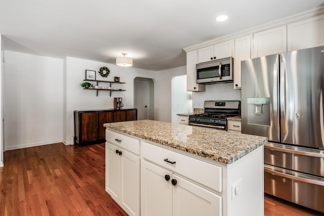 410 Acton Rd, Columbus, OH 43214 - kitchen featuring appliances with stainless steel finishes, arched walkways, dark wood-style floors, light stone counters, and a kitchen island