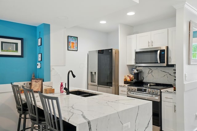 2201 Teardrop Ave Unit 34A, Columbus, OH 43235 - kitchen featuring stainless steel appliances, a sink, light stone counters, white cabinets, and decorative backsplash