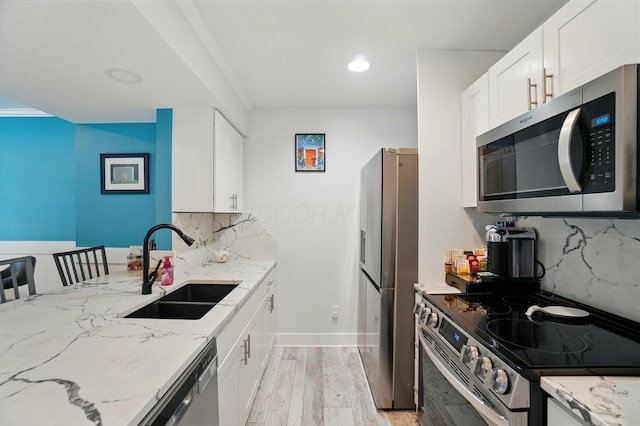 2201 Teardrop Ave Unit 34A, Columbus, OH 43235 - kitchen featuring appliances with stainless steel finishes, a sink, light stone countertops, light wood-style floors, and backsplash