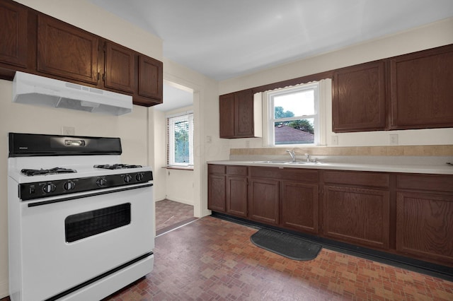 2007 Dunbar Dr, Columbus, OH 43224 - kitchen with white gas range oven, under cabinet range hood, light countertops, and dark brown cabinetry