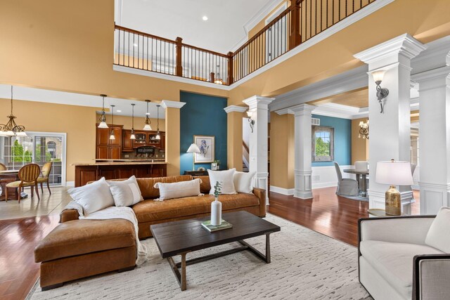 5753 Aster Way, Galena, OH 43021 - living room with decorative columns, wood finished floors, a towering ceiling, crown molding, and a chandelier