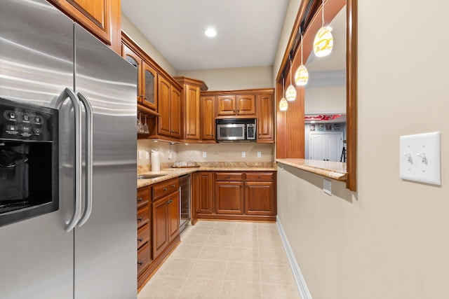 5753 Aster Way, Galena, OH 43021 - kitchen featuring appliances with stainless steel finishes, brown cabinets, light stone counters, light tile patterned floors, and decorative backsplash