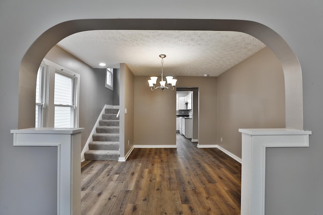 212-214 S Eureka Ave, Columbus, OH 43204 - unfurnished dining area with arched walkways, a textured ceiling, baseboards, stairway, and dark wood-type flooring