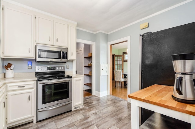 138 E Kelso Rd, Columbus, OH 43202 - kitchen with appliances with stainless steel finishes, white cabinets, wood tiled floors, and crown molding