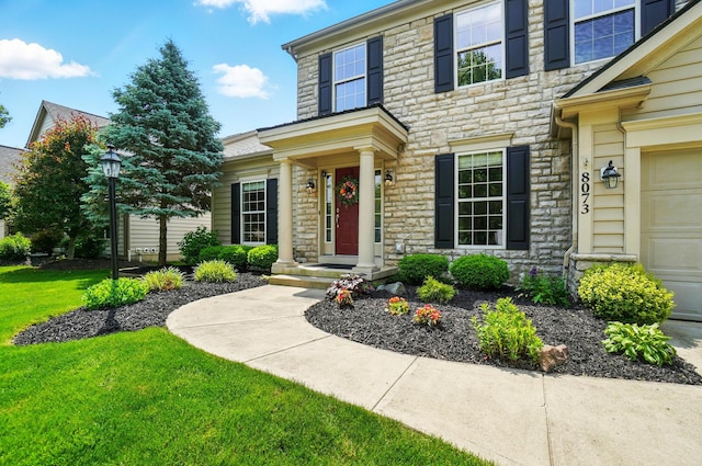 8073 Tree Lake Blvd, Powell, OH 43065 - view of front facade with stone siding, a garage, and a front yard