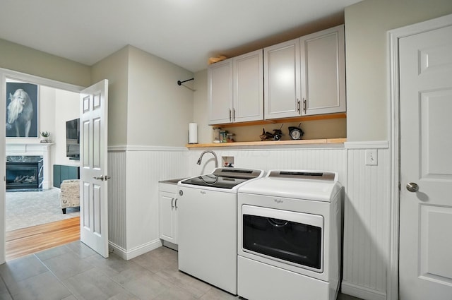 8073 Tree Lake Blvd, Powell, OH 43065 - washroom featuring washing machine and dryer, cabinet space, wainscoting, and a premium fireplace