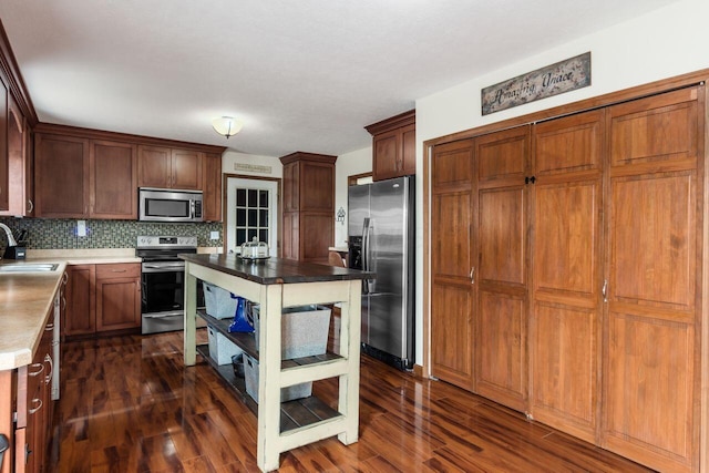 1875 Madden Higgins Rd, London, OH 43140 - kitchen with appliances with stainless steel finishes, a sink, dark wood-style floors, decorative backsplash, and light countertops