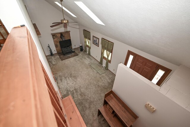 5467 Timpson Rd, Caledonia, OH 43314 - carpeted living area with a skylight, a wood stove, ceiling fan, lofted ceiling, and a textured ceiling