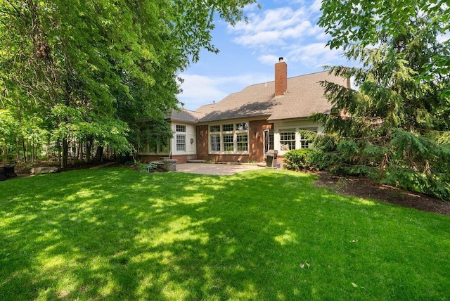 8467 Tartan Fields Dr, Dublin, OH 43017 - back of house featuring a patio, a chimney, a yard, roof with shingles, and brick siding