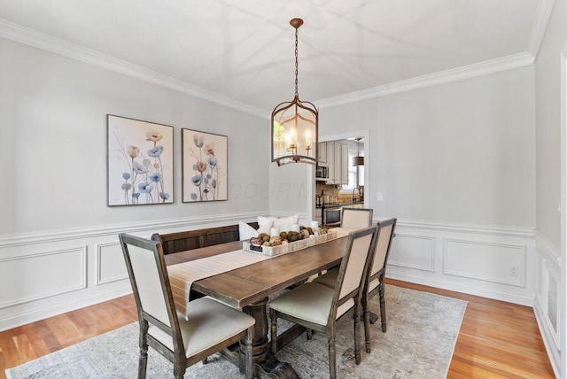 8467 Tartan Fields Dr, Dublin, OH 43017 - dining room with light wood-type flooring, a chandelier, ornamental molding, and a wainscoted wall