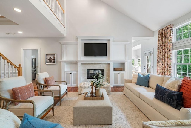8467 Tartan Fields Dr, Dublin, OH 43017 - living room with high vaulted ceiling, stairway, light wood-style flooring, recessed lighting, and a glass covered fireplace