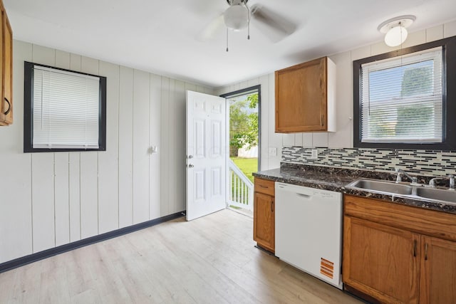 147 Schultz Ave, Columbus, OH 43222 - kitchen with white dishwasher, dark countertops, brown cabinetry, light wood-type flooring, and backsplash