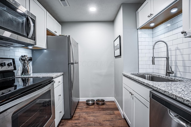 955 E Mound St, Columbus, OH 43205 - kitchen with appliances with stainless steel finishes, a sink, dark wood finished floors, light stone counters, and a textured ceiling