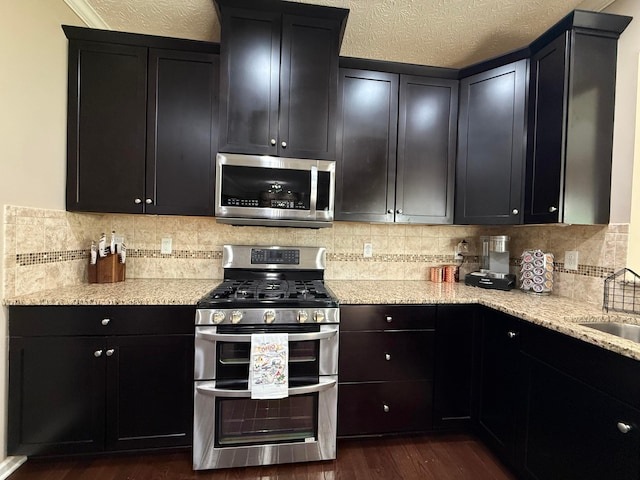 150 Shawnee Dr, Pickerington, OH 43147 - kitchen featuring stainless steel appliances, dark cabinets, dark wood-style floors, light stone counters, and tasteful backsplash